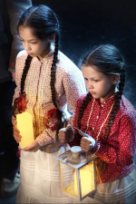 fot. Dorota Awiorko / [Dwie dziewczynki w strojach ludowych, z długimi warkoczykami, trzymające przed sobą świece.]