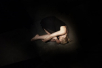 fot. Dorota Awiorko / [Ujęcie z góry. Jasnowłosa kobieta, w krótkiej czarnej sukience na ramiączkach leży w pozycji embrionalnej.]