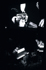 fot. Wojciech Nieśpiałowski / [W dolnej części zdjęcia muzyk przy fortepianie. Nad nim ekran z wyświetlonym slajdem prezentującym dłonie trzymające stare zdjęcia.]