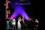 fot. D.Awiorko [Sztuczna trawa na scenie. Po lewej dwie kobiety w kolorowych sukienkach, trzymające mikrofony, dalej zwróceni do siebie kobieta i mężczyzna. Po prawej pianista. Na drugim planie gitarzysta, perkusista i basista.]